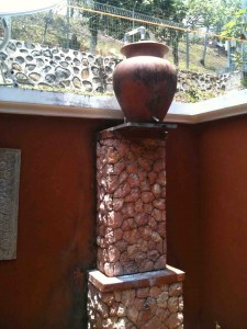 Traditional Sasak hot water clay pot perched high to absorb summer heat with tap at base for showering under